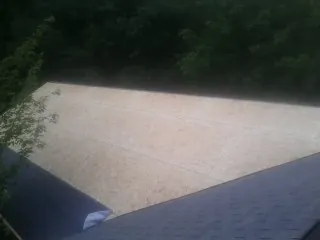 New OSB roof sheathing installed beside an existing shingle roof in Old Station