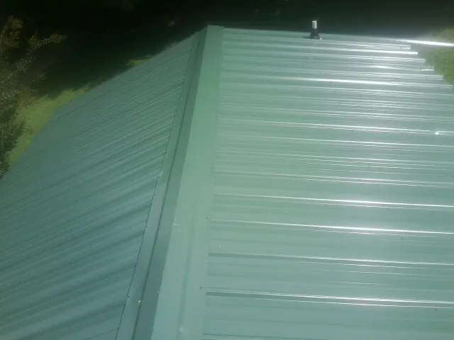 New green metal panels meeting at the ridge of a roof — Flat Roof Repair work by our crew in Old Station