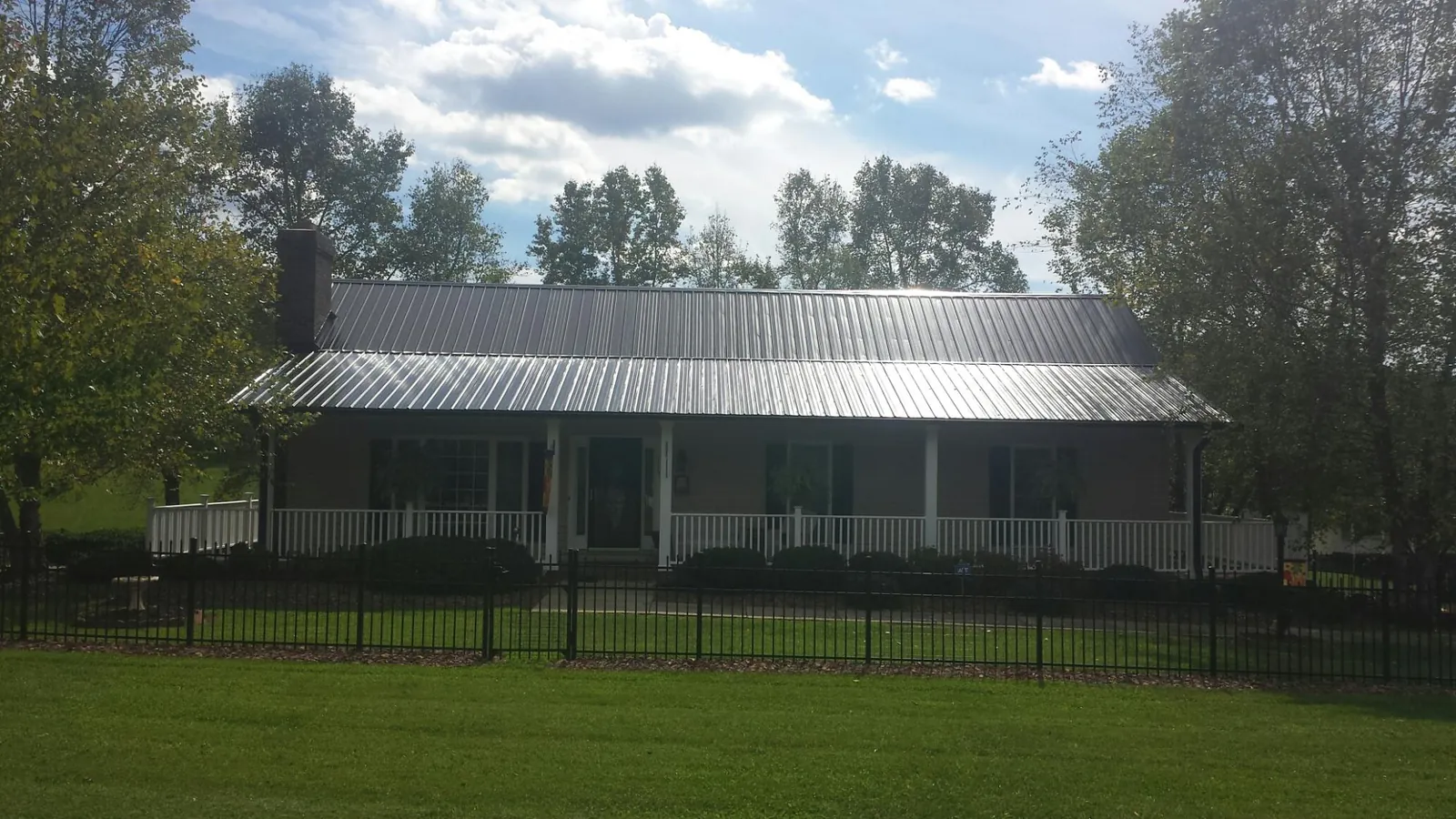 Gray metal roof on a brick ranch with a full width front porch — Gutter Guard Installation work by our crew in Old Station