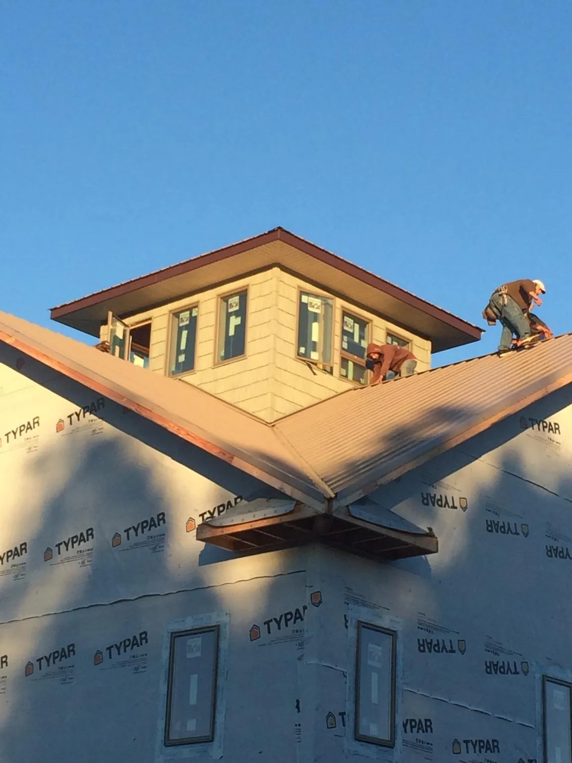 Roofers working around a rooftop cupola on a new metal roof at sunset — Roof Waterproofing in Old Station by Roofing Brothers
